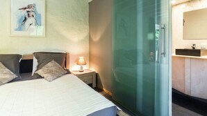 A bedroom with a bed, bedside table, lamp, and a painting on the wall. - Charming Retreat, Veldegem (Zedelgem - Veldegem)