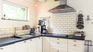 A kitchen with white cabinets, a black countertop, a stainless steel range hood, and a window with a view of greenery. - Charming Retreat, Veldegem (Zedelgem - Veldegem)