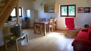 A cozy living room with a wooden ceiling, a dining area with a table and chairs, a red sofa, and a kitchen area with appliances. - Chalet in Dabo near Castle Ruins (La Hoube (dabo))
