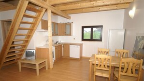 A compact kitchen with wooden cabinets, a dining table with chairs, a built-in stove, and a small TV. - Chalet in Dabo near Castle Ruins (La Hoube (dabo))