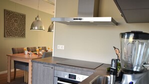 Une cuisine moderne équipée d’un lave-vaisselle encastré, d’un mixeur et d’un coin repas avec une table et des chaises.