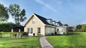 Une maison à deux étages avec une allée pavée menant à un patio couvert.