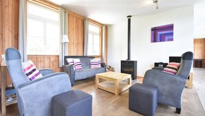 Un salon chaleureux avec un canapé, deux fauteuils, une table basse et un poêle à bois.
