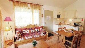 Un espacio habitable compacto con sofá, mesa de comedor y kitchenette.