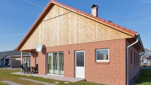 Een modern gebouw met een houten gevel en een bakstenen gedeelte, voorzien van grote ramen en een schotelantenne.