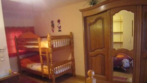 Ein Schlafzimmer mit Etagenbett, Holzschrank und Spiegel.