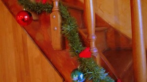 Eine Holztreppe mit einem Girlanden-Schmuck aus Grünpflanzen und roten Verzierungen.