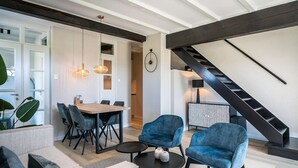 Een moderne woonkamer met een eethoek, een trap en een grote plant.
