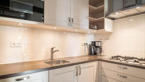 Een moderne keuken met roestvrijstalen apparatuur, een dubbele spoelbak en een gasfornuis.