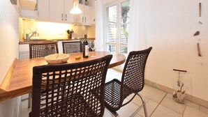 Una cocina moderna con armarios blancos, una mesa de comedor de madera y sillas de mimbre negro.