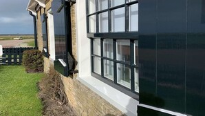 Un bâtiment à la façade en briques, aux encadrements de fenêtres blancs et à l’auvent noir.