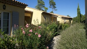 En række gule bygninger med tegltage, omgivet af grøn vegetation og træer.