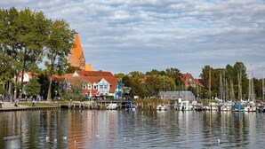 Een waterkant met boten, een kerk en een steiger met mensen.