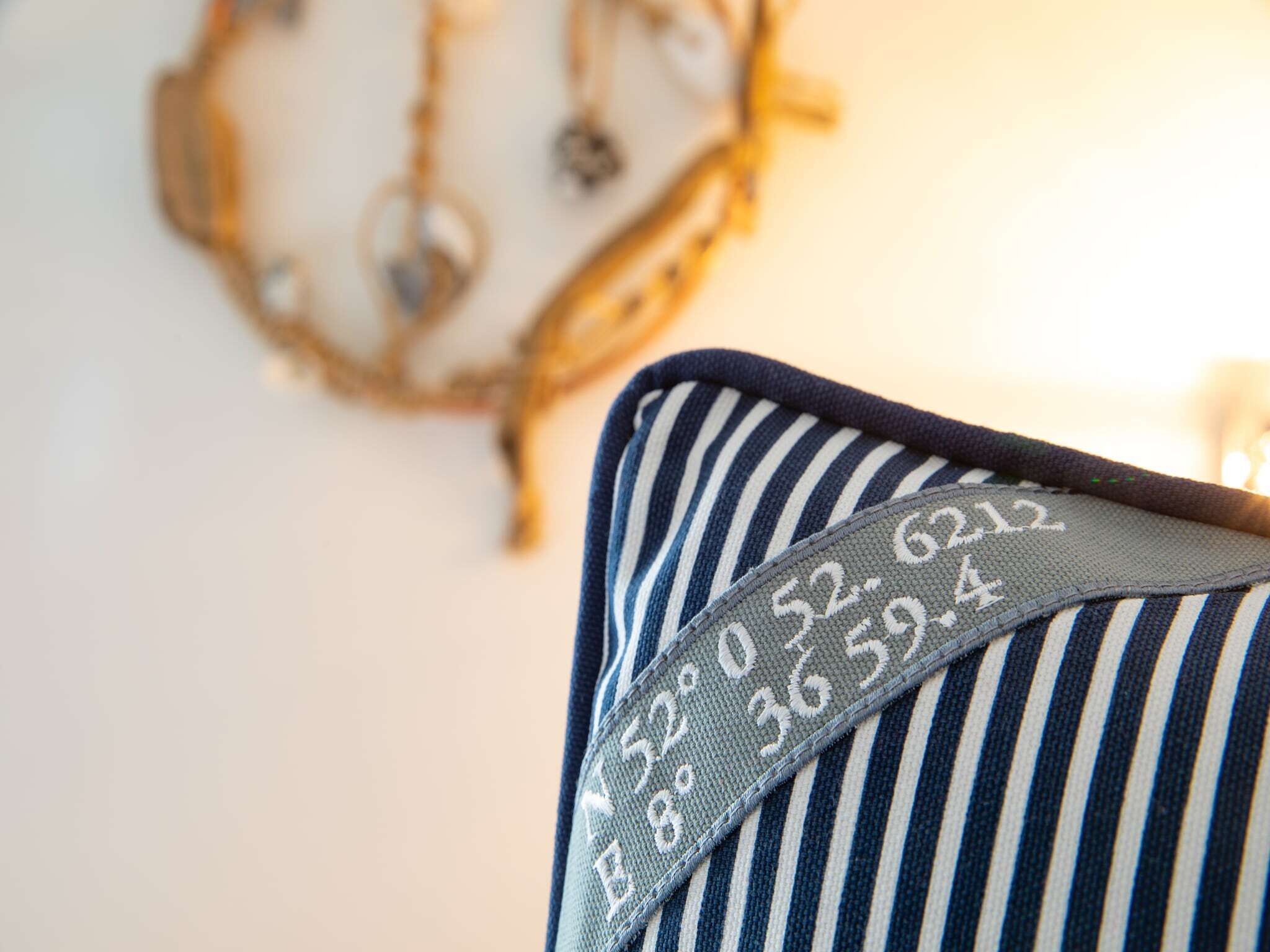 A striped pillow with a pattern of numbers and a decorative wall hanging in the background.