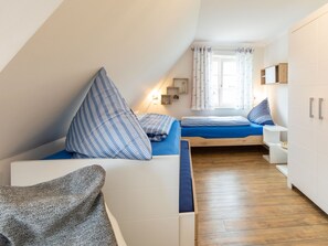 Une chambre à coucher compacte et moderne, dotée d’un lit en mezzanine, d’une petite table de chevet et d’une armoire.