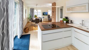 Een moderne keuken met een centraal eiland, witte kasten en een accentmuur van baksteen.