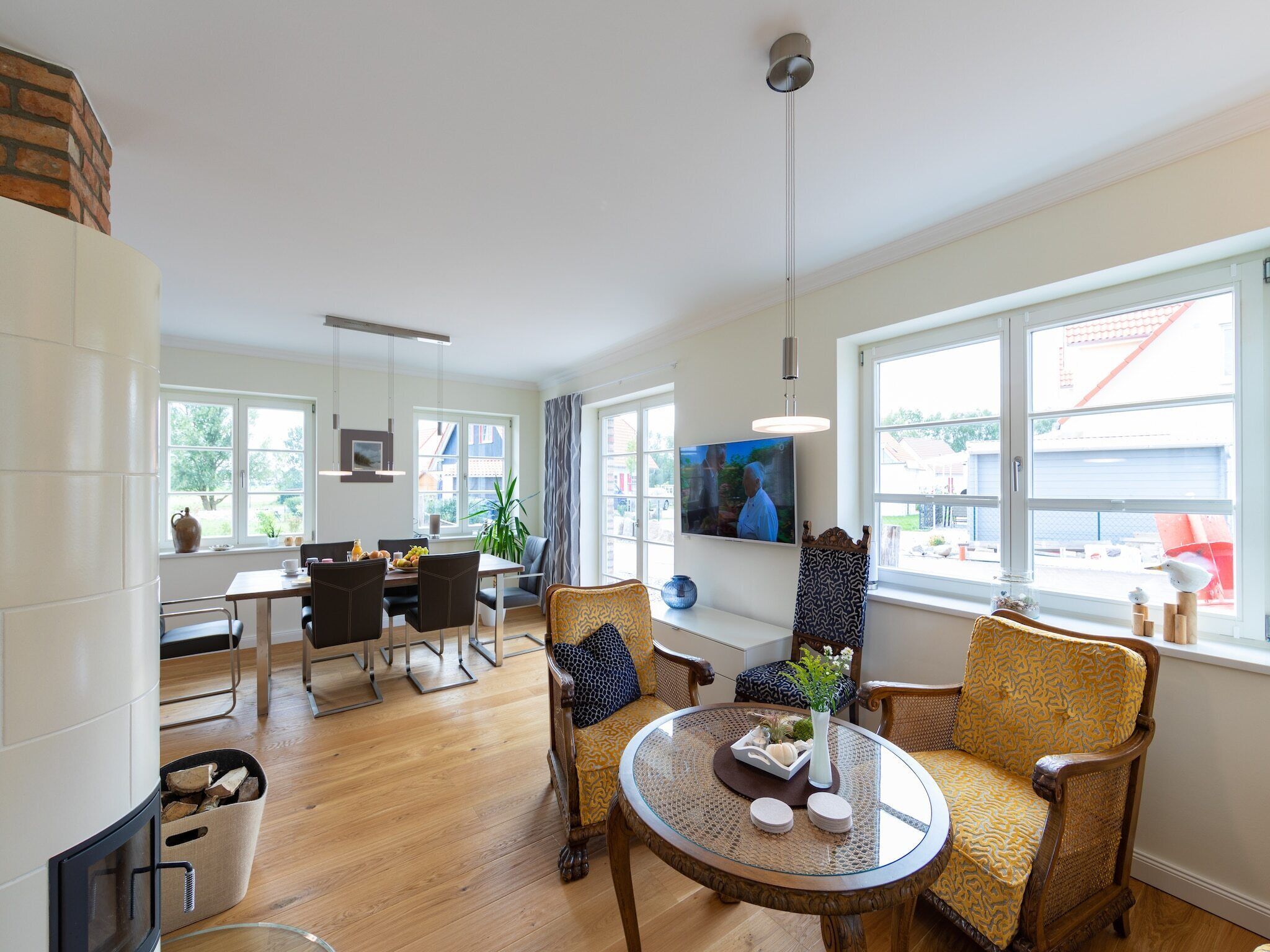 A modern living room with a fireplace, dining area, and large windows.