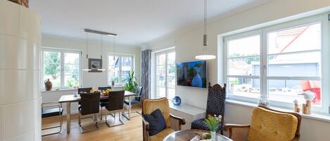 A modern living room with a fireplace, dining area, and large windows.