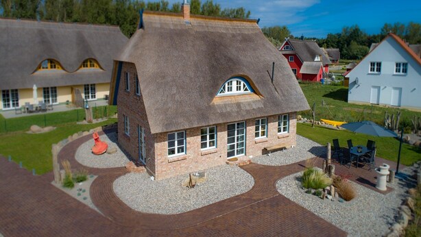 Een huis met een steil dak, een bakstenen gevel en een grindpad.