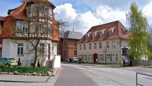 A street with traditional European architecture, including a building with a tower and another with a sloped roof. - Apartment in Bad Doberan mit Garten (Bad Doberan)