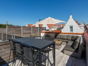 Une terrasse extérieure avec une table et des chaises, un canapé et un grand parasol.