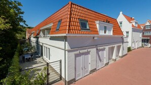 Ein Wohngebäude mit rotem Ziegeldach, weißen Außenwänden und einem verschlossenen Eingang.
