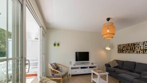 Ein modernes Wohnzimmer mit Fernseher, einer Couch und Korbsesseln.