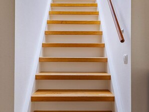A wooden staircase with a handrail, leading to an upper floor.
