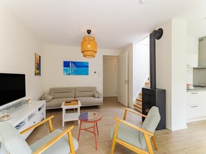 En moderne stue med sofa, fjernsyn, sofabord og pejs.