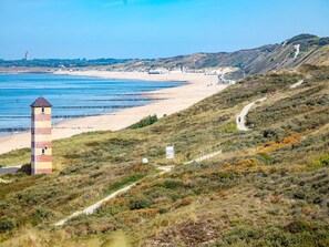 Un paysage côtier comprenant une plage, un phare et un sentier de randonnée.