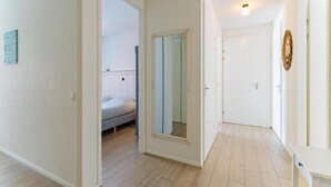 Ein Flur mit einem Bett, einem Spiegel und einer Tür zu einem weiteren Zimmer.