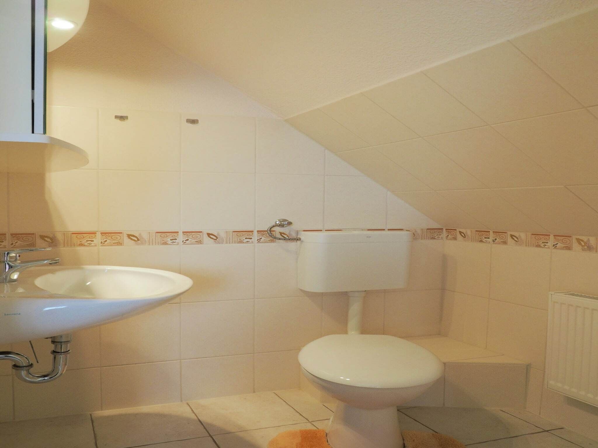 Ein Badezimmer mit weißem Waschbecken, Toilette und gefliesten Wänden.