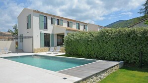 Ein modernes, zweistöckiges Haus mit Schwimmbad, Kiesweg und einem gepflegten Garten.