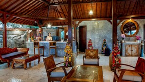 A traditional wooden interior with a reception desk, seating area, and decorative statues. - Campuhan Sebatu Resort (Sebatu)
