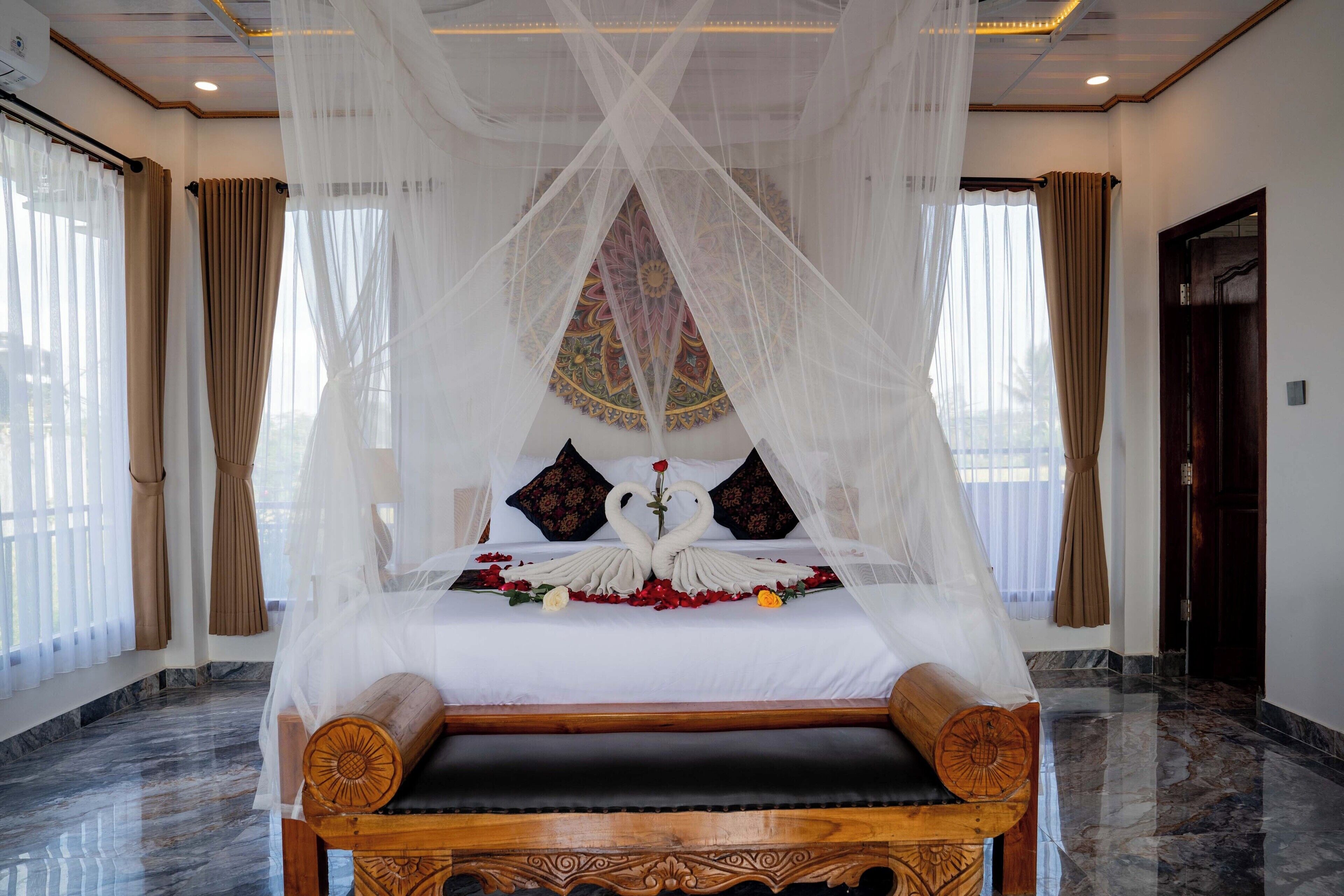 A four-poster bed with a canopy, a wooden bench, and a decorative wall hanging.