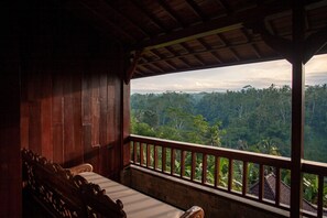 A wooden room with a bench and a view of a lush forest.