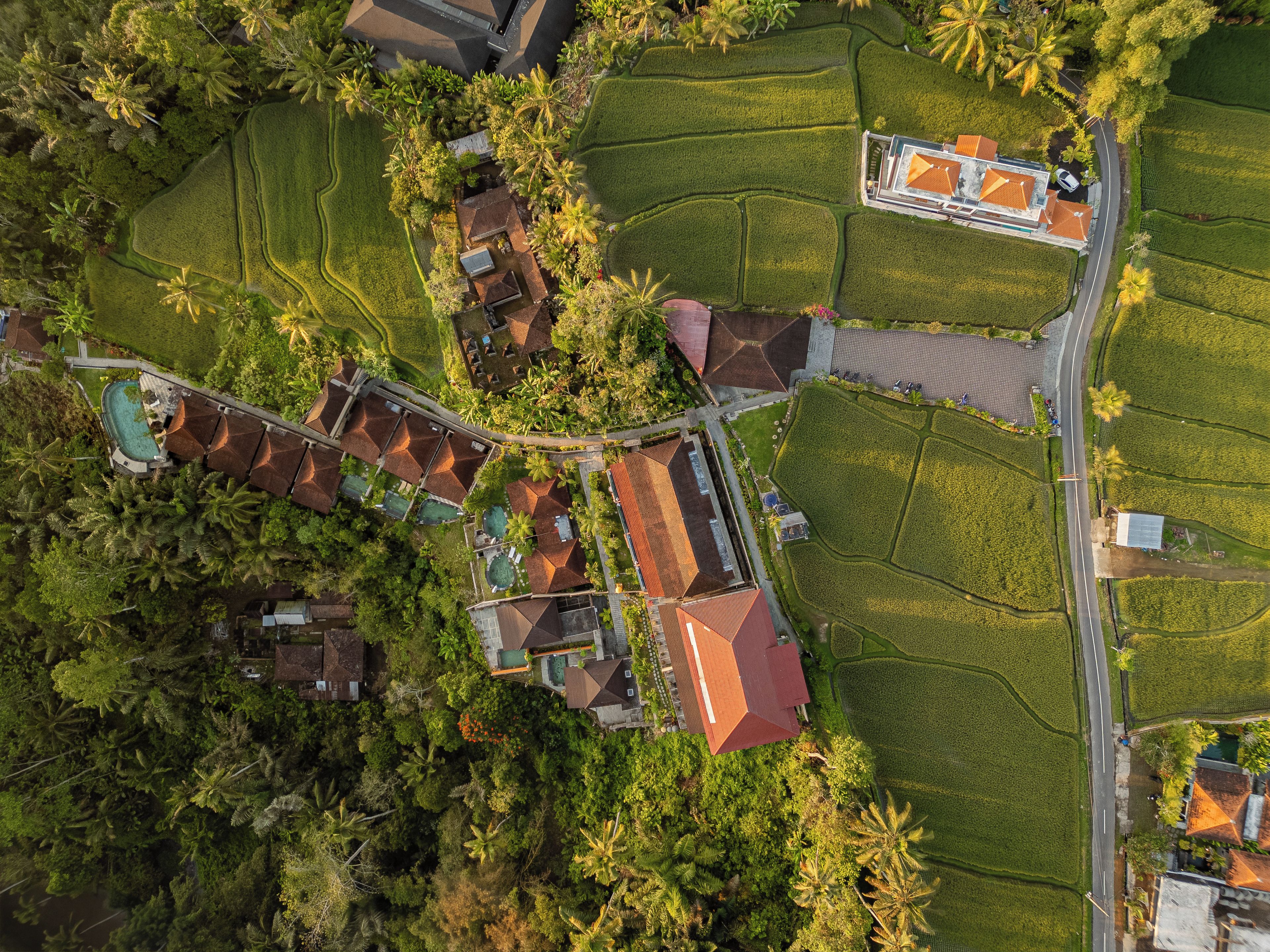 An aerial view of a resort with multiple buildings, a swimming pool, and surrounding lush greenery.