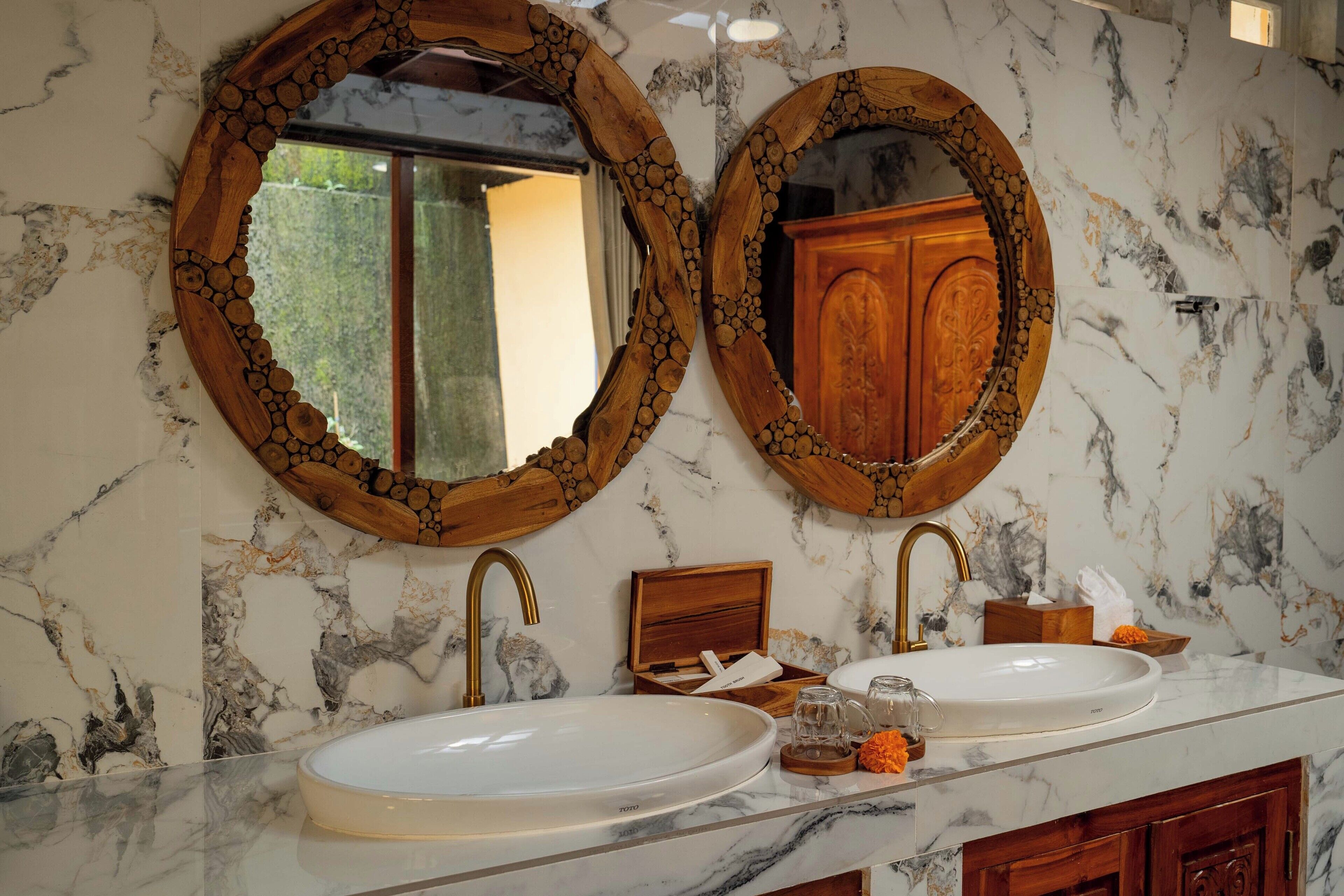A bathroom with two oval mirrors with wooden frames, a white sink, and a wooden cabinet.