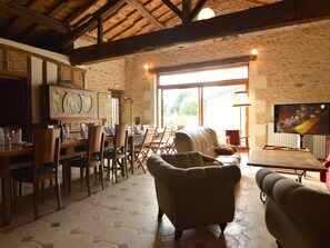 A rustic interior with a dining area, sofas, and a television.