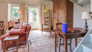 Una habitación rústica con sofá rojo, aparador de madera y una escalera.