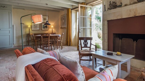 Una sala de estar acogedora con chimenea, un comedor con mesa y sillas, y un sofá con cojines.