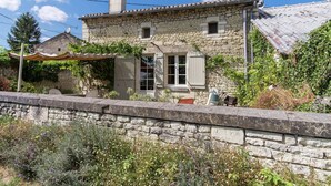 Una casa de piedra con techo de tejas, una chimenea y una ventana pequeña.