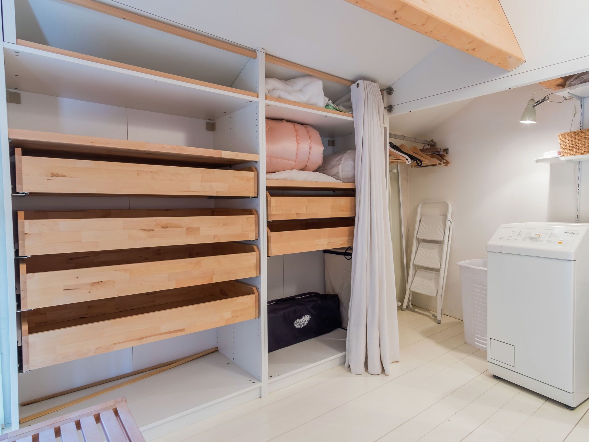 Ein Schlafzimmer mit Einbauschrank, Waschmaschine und Bett mit Vorhang.