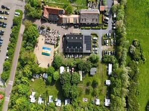 An aerial view of a campground with RVs, a beach area, and a building with solar panels. - Apartment in Vrouwenpolder near the Beach (Vrouwenpolder)