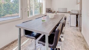 Una cocina moderna con comedor, ventanas amplias y vistas a zonas verdes.