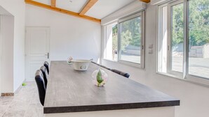 Cocina moderna con una isla grande, muebles blancos y vistas al exterior a través de amplias ventanas.