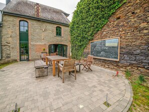 A stone building with a green door, a wooden table and chairs, and a chalkboard with 'PARTY TIME' written on it. - Riverside Villa with Charm (Léglise)