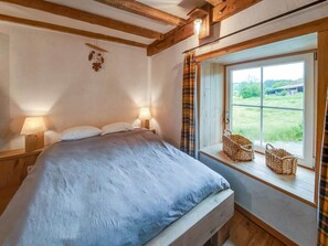 A bedroom with a bed, two bedside lamps, a window with a view of greenery, and a basket on the windowsill. - Riverside Villa with Charm (Léglise)