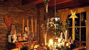 A cozy dining area with a wooden table set for a meal, surrounded by candles, a Christmas tree, and various decorations. - Riverside Villa with Charm (Léglise)
