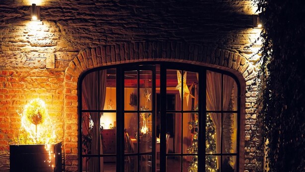 A stone-walled building with a large arched doorway leading into a warmly lit interior. - Riverside Villa with Charm (Léglise)